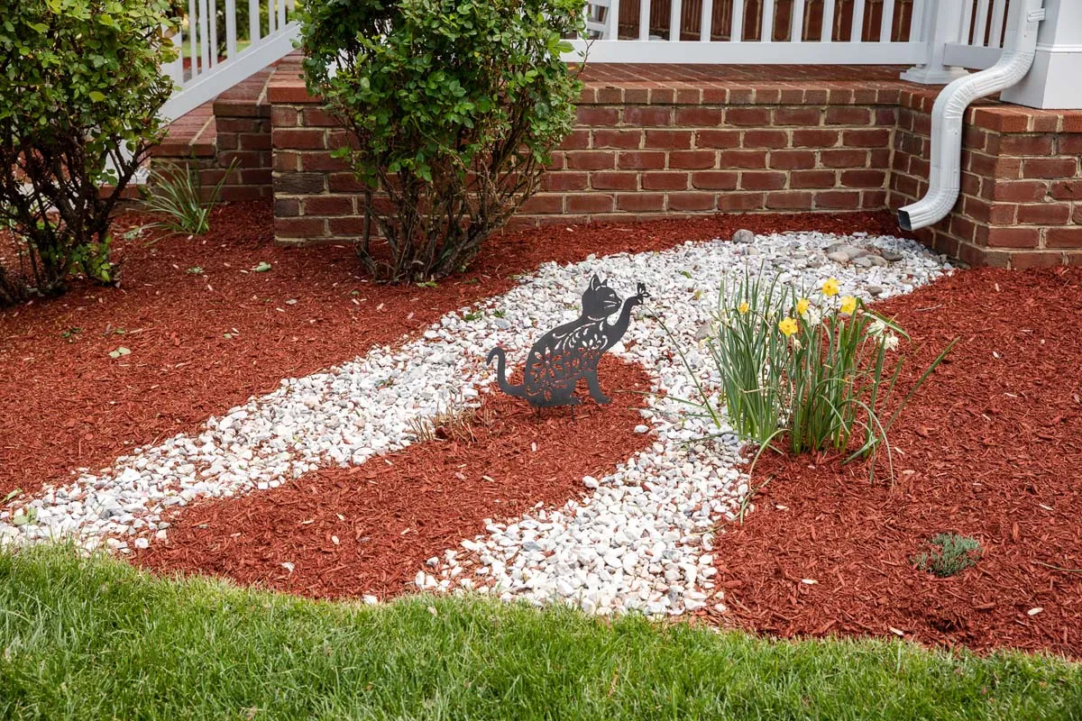 An image of a lawn with a cat statue on display playing with a plant
