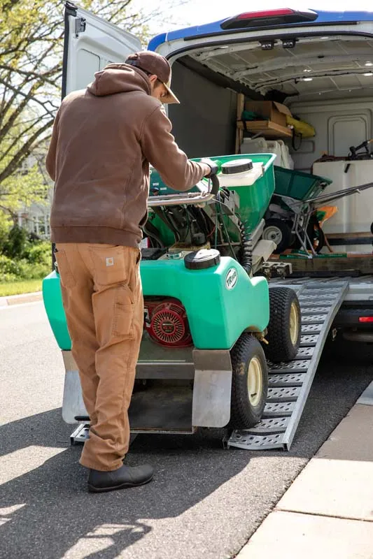 employee loading lawn mower into van