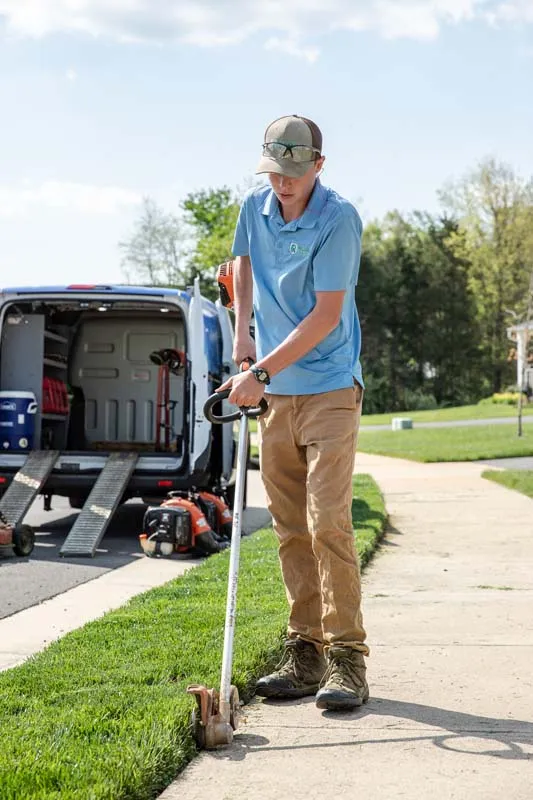 Employee edging the lawn's sidewalk